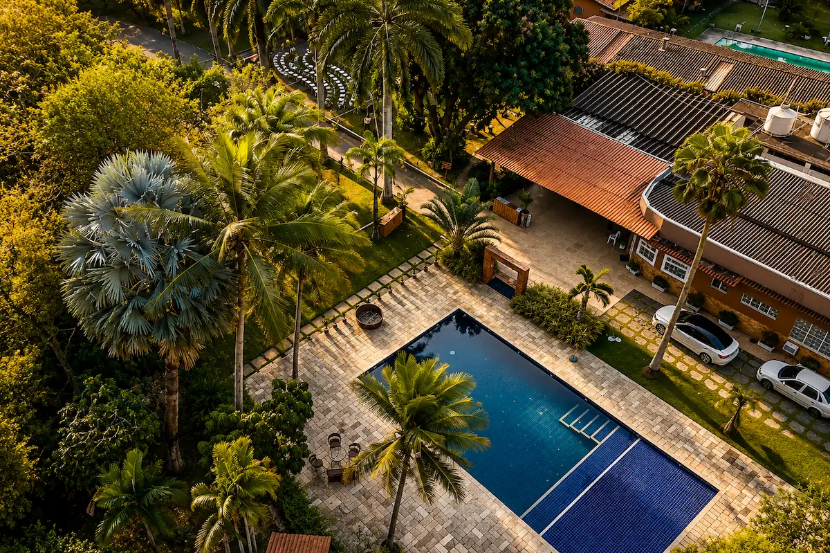 Vista aérea da piscina e área externa entre palmeiras