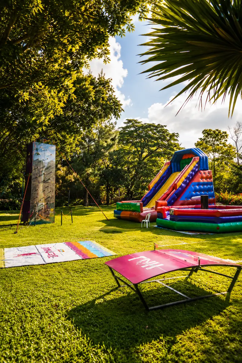 Área externa com brinquedos infantis, escorregador inflável e parede de escalada no gramado